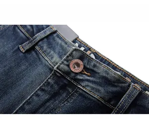 Macro view of dark blue denim jeans waist with retro copper button and stitching details