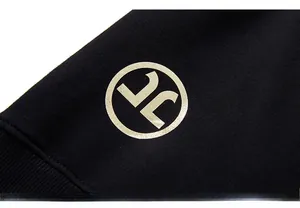 Close-up of golden metallic circular logo printing on black cotton sweatshirt fabric