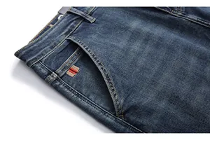 Detail of blue denim jeans featuring vintage wash texture and striped embroidery patch