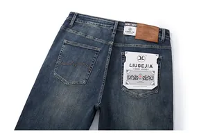 Detailed view of blue washed denim back pocket with brown leather patch and stitching