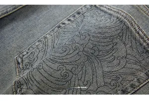 Close-up of heavy denim fabric with intricate paisley jacquard and double stitching