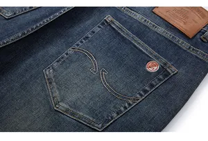 Macro shot of denim back pocket with brown leather patch and red embroidery detail
