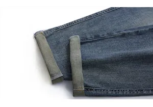 Close-up of rolled hems on dark blue vintage washed straight-leg denim jeans for men