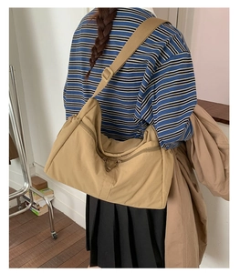 Model view of large khaki canvas crossbody bag showing spacious capacity and wide strap