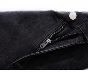 Macro detail of high-quality YKK metal zipper and vintage button on black denim jeans