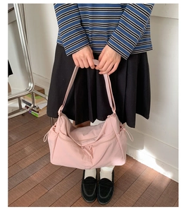 Pink nylon tote bag detail with front zipper pocket and adjustable strap on a model