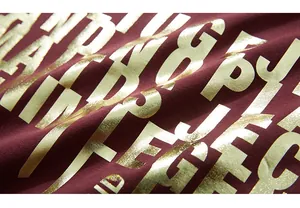 Gros plan de l'impression métallique dorée sur t-shirt en coton bordeaux à manches