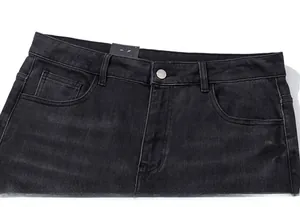 Detail of waist area featuring silver button and stitching on black washed denim jeans