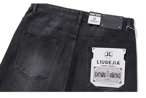 Detail of vintage washed dark gray jeans featuring a black leather back patch and pocket