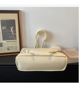 Détail du sac à bandoulière en similicuir crème avec une sangle décorative à boucle métal