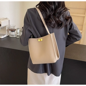 Dettaglio della borsa tote in pelle martellata taupe con chiusura dorata in un caffè moderno