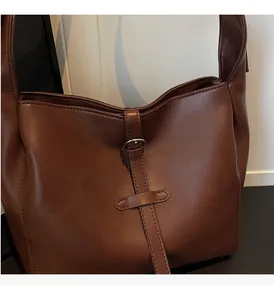 Detailed shot of dark brown leather tote with silver metal buckle and fine stitching