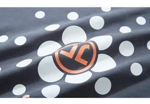 Detailed close-up of dark grey fabric with white polka dots and orange floral logo design