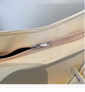 Détail de la fermeture éclair en métal argenté et des coutures sur le sac cabas en cuir beige