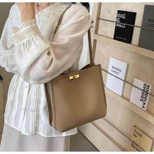 Dettaglio borsa tote in pelle marrone con chiusura a scatto dorata e trama a grana
