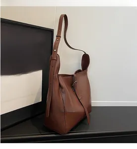 Detail view of a vintage brown leather handbag with metal buckle and adjustable strap
