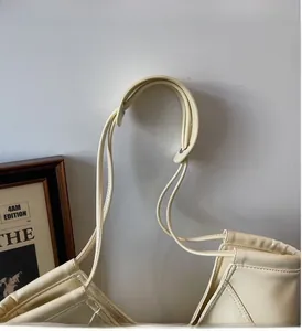Gros plan de la bandoulière en cuir crème avec œillets métalliques et coutures de luxe