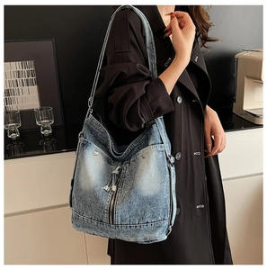 Détail d'un sac hobo en jean bleu avec rivets vintage et fermetures éclair décoratives