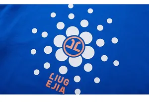 Detail of blue knitted cotton fabric featuring floral graphic print and orange lettering