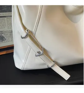 Détail du sac cabas crème avec sangle latérale et boucle à anneau en métal argenté