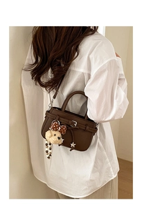 Detail of brown litchi pattern leather bag with cute puppy plush charm and star pendant