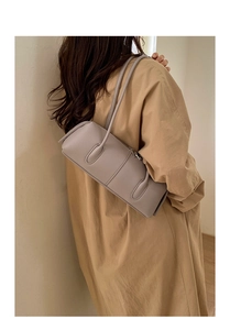 Side view of woman wearing a grey vintage tote bag with sleek leather shoulder straps