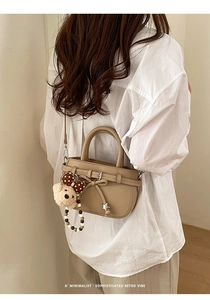 Detail of khaki leather mini bag with bow decoration and cute plush bear charm
