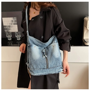 Détail du sac hobo en jean bleu avec fermeture éclair verticale et bandoulière réglable