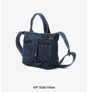 Side view of dark blue denim handbag featuring classic orange stitching and pockets