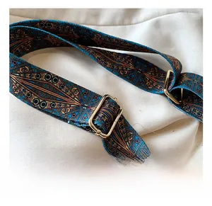 Dettaglio della tracolla larga regolabile con motivo boho intrecciato e fibbie in metallo oro