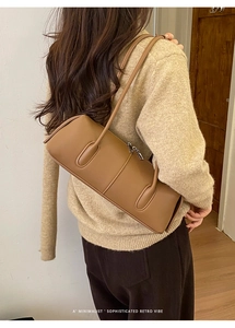 Detail of brown leather cylindrical shoulder bag showing stitching and texture