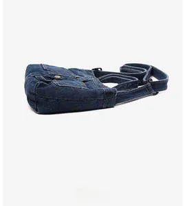 Side view of dark blue denim crossbody bag showing fabric texture and pocket detail