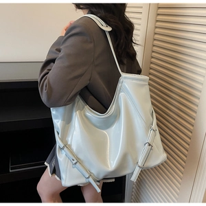 Gros plan d'un sac cabas en cuir verni bleu clair avec boucles métalliques argentées