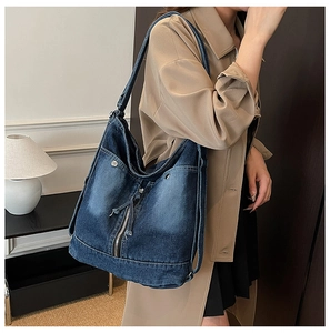 Détail du sac cabas en denim lavé vintage avec rivets métalliques et large bandoulière