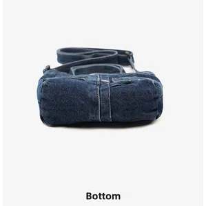 Close-up detail of the rectangular denim base and durable stitching on blue crossbody bag