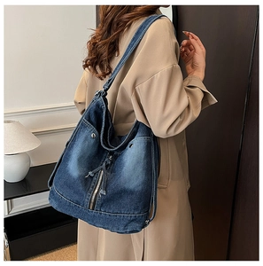 Détail d'un sac cabas en denim bleu délavé avec texture vintage et accents zippés