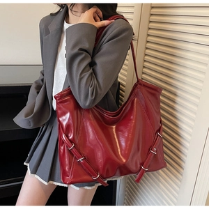 Sac fourre-tout en cuir rouge sur modèle montrant une grande capacité et une finition mate