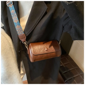 Dettaglio di borsa a cilindro marrone con ampia tracolla colorata stile bohémien