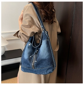 Détail du sac fourre-tout en denim bleu délavé vintage avec poches multiples et zips argentés