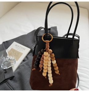 Detail of a two-tone bucket bag with quilted suede and a colorful beaded tassel charm