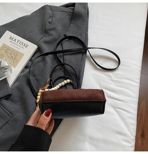 Detail of two-tone suede bucket bag with quilted texture and decorative bead chain