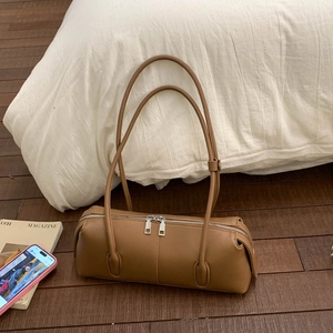Detail of caramel cylindrical shoulder bag with silver double zippers on wood background