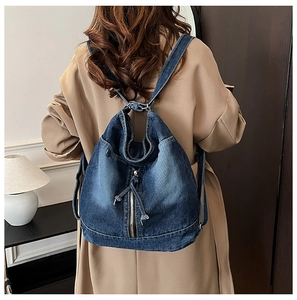 Détail d'un sac à dos en denim avec fermeture éclair en métal et cordon de serrage