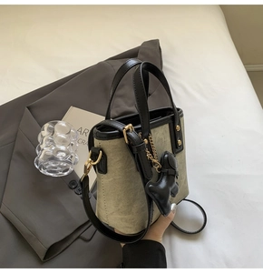Dettaglio mini borsa tote in tela con finiture in pelle nera e ciondolo a cucciolo
