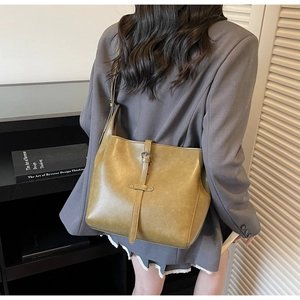 Detail of olive green vintage bucket bag showing glossy texture and decorative buckle strap