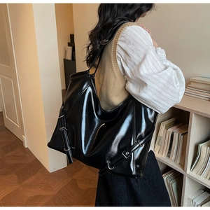 Grand sac cabas noir brillant avec boucle latérale réglable dans un cadre moderne
