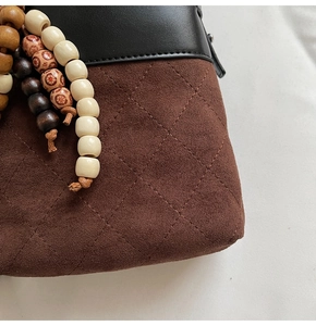 Detail of dark brown suede bucket bag featuring quilted pattern and ethnic wooden beads