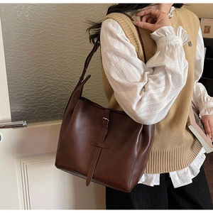 Close-up of a vintage dark brown leather tote bag featuring elegant buckle strap detail
