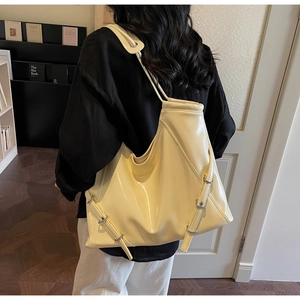 Détail d'un grand sac cabas crème avec des brides réglables à boucles métalliques et vernis