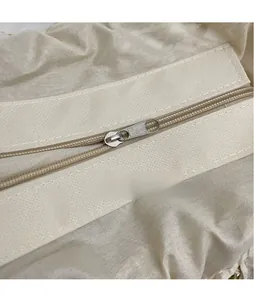 Detail shot of smooth silver zipper pull and durable beige woven fabric texture